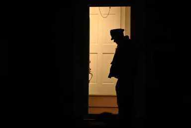 Silhouette of police officer standing in doorway of crime scene